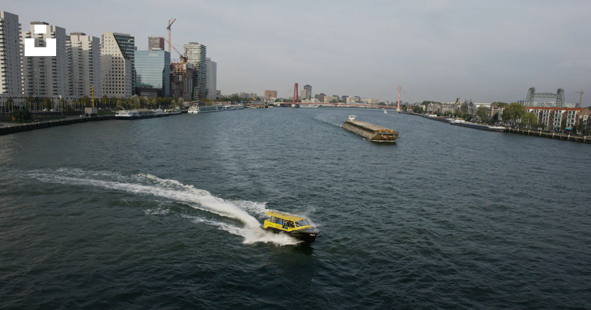 A Yellow Boat Traveling Down A River Next To Tall Buildings Photo a-yellow-boat-traveling-down-a-river-next-to-tall-buildings-photo