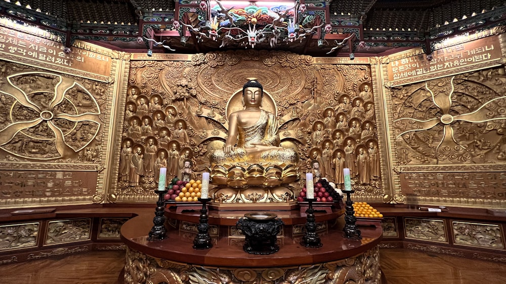 a golden buddha statue sitting on top of a wooden table