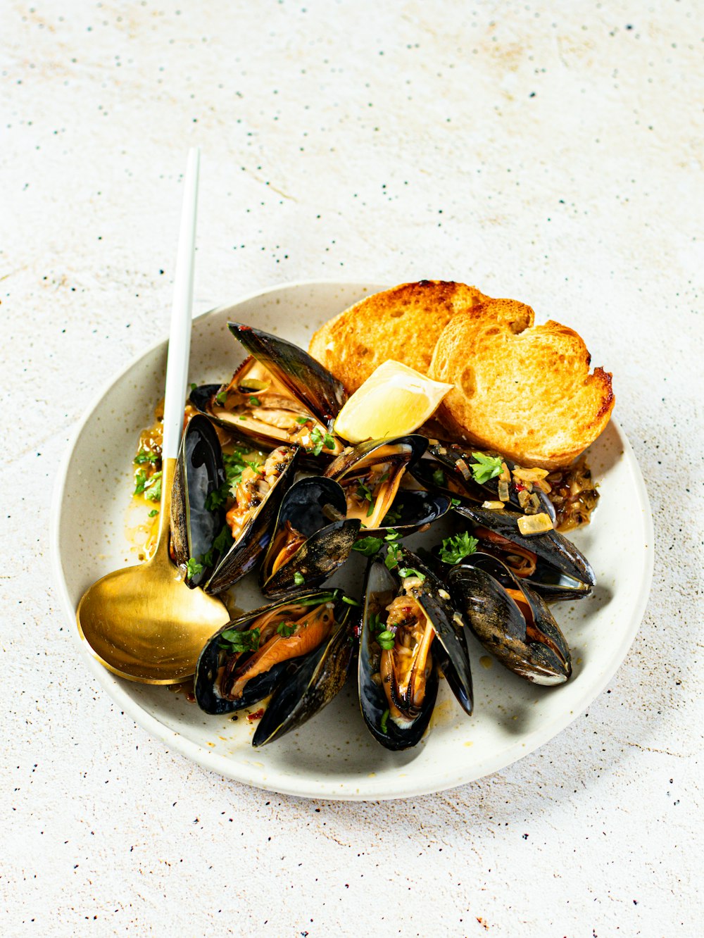 a white plate topped with mussels and bread
