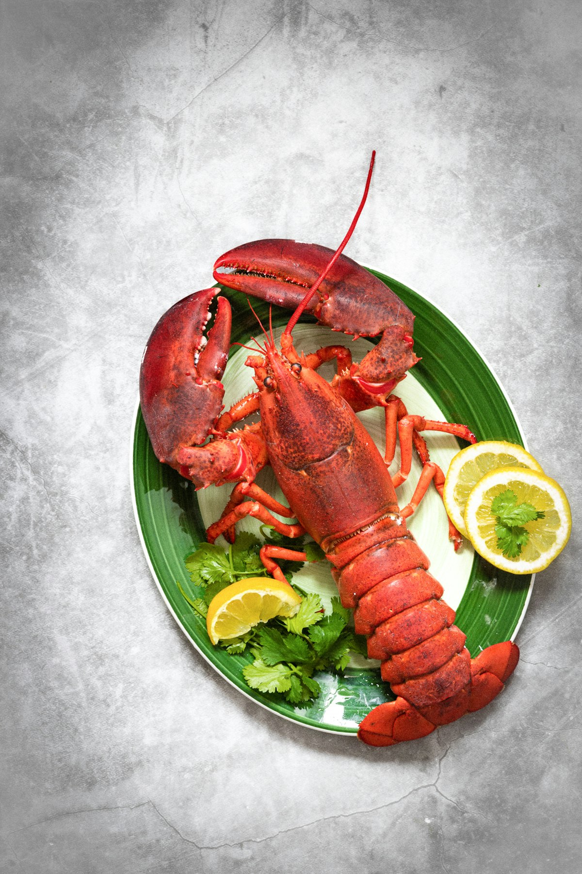 A plate of lobsters with lemons and fresh herbs