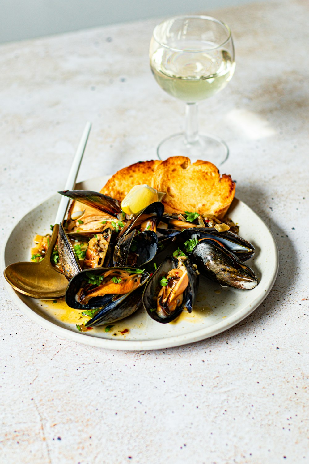 a plate of mussels and bread with a glass of wine