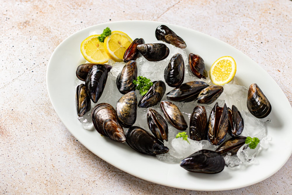 a white plate topped with mussels and lemon wedges