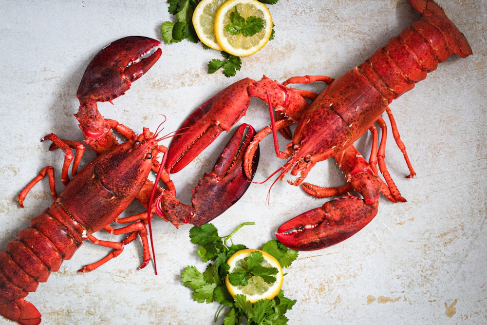 a cooked lobster on a cutting board with lemons and parsley