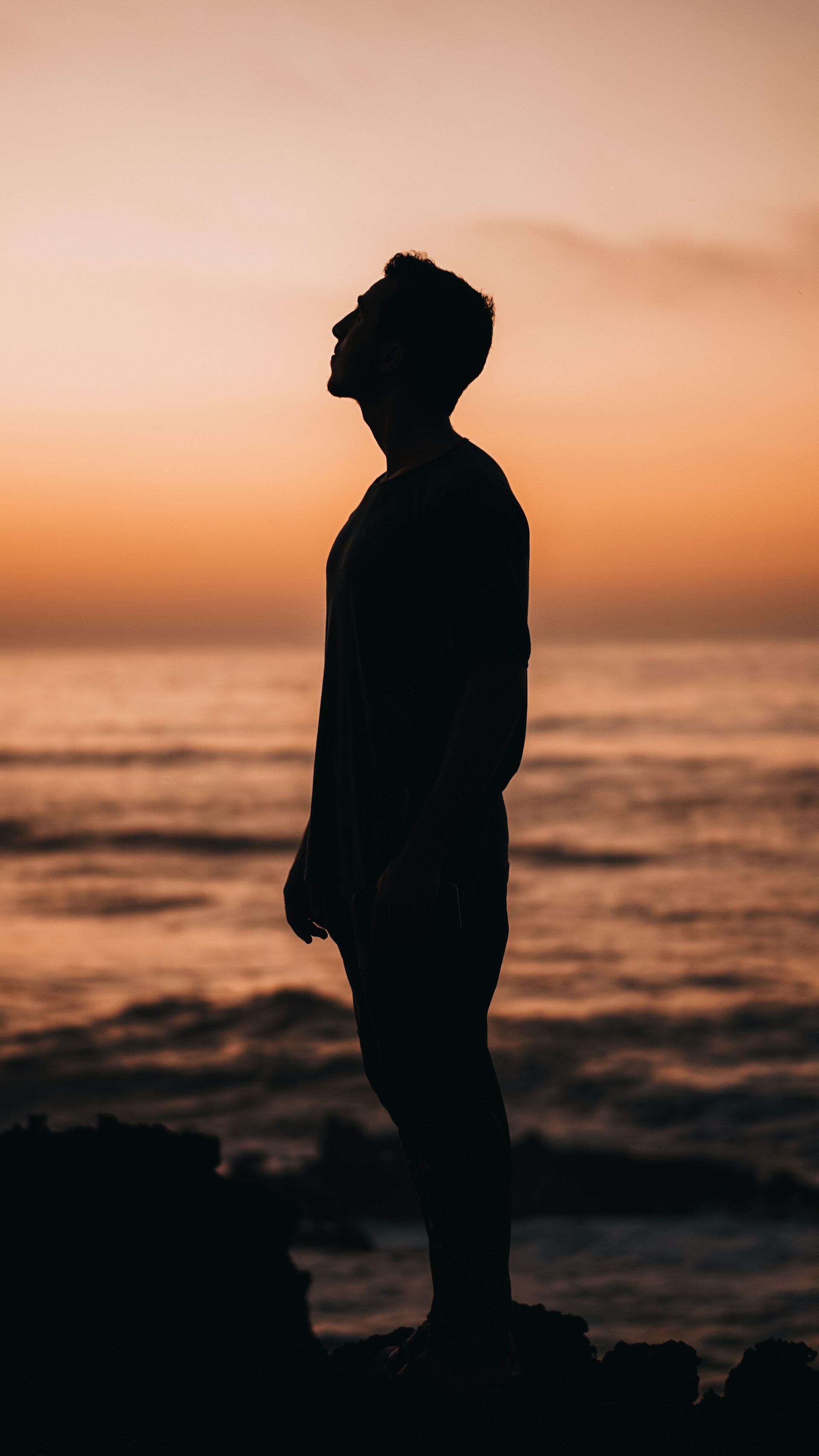 a man standing on top of a beach next to the ocean