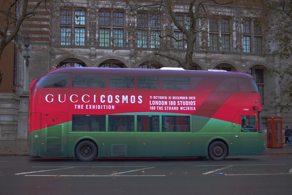 a green and red double decker bus parked in front of a building