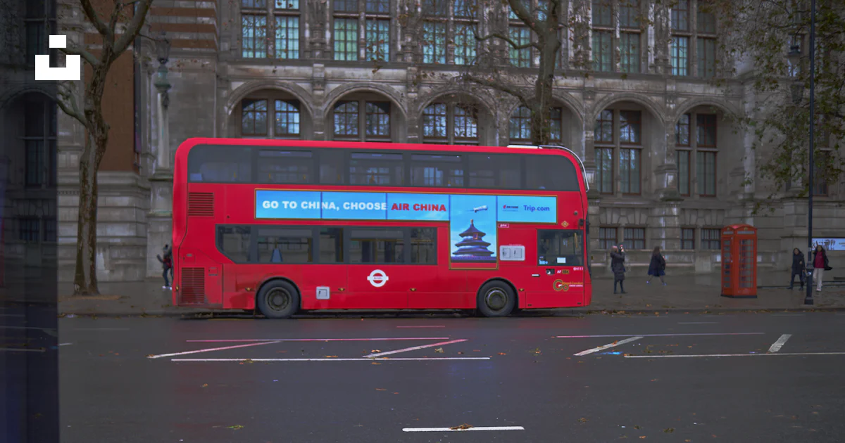 A red double decker bus parked in front of a building photo – Free Bus ...