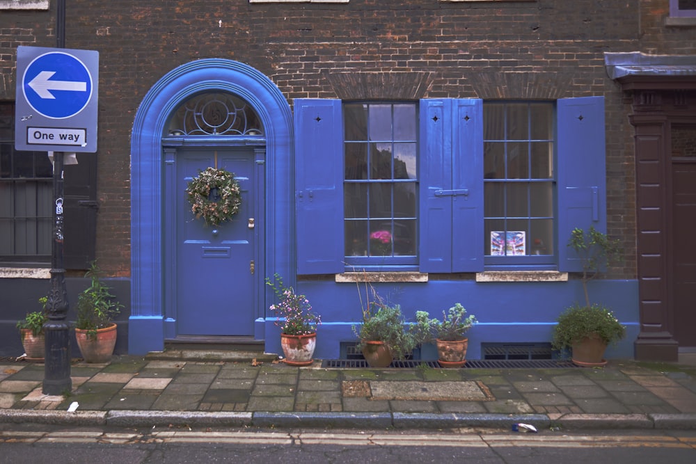 a blue building with potted plants and a street sign