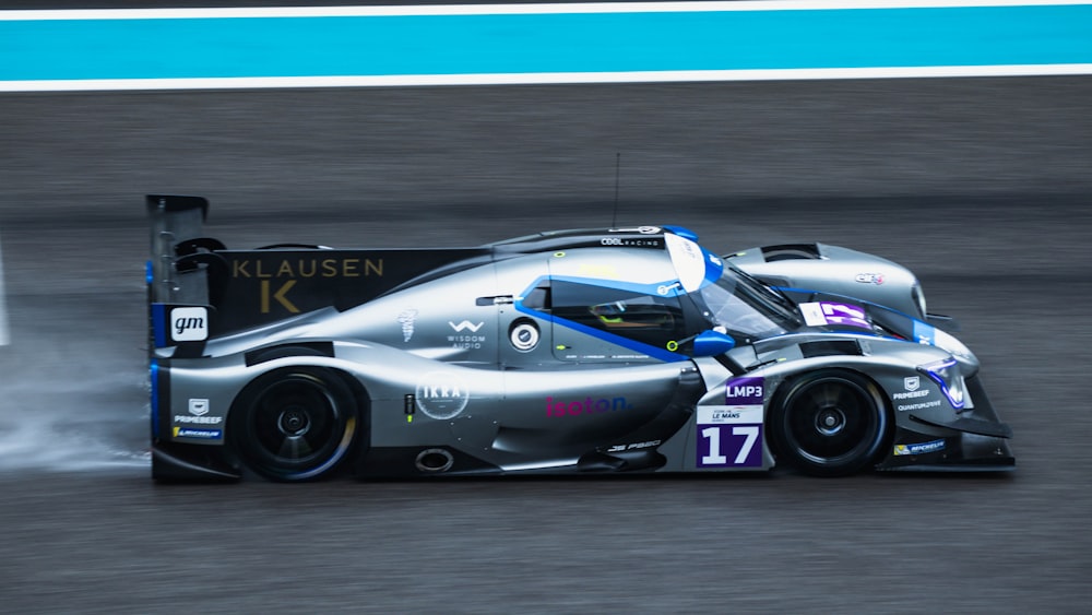 a silver race car driving down a race track