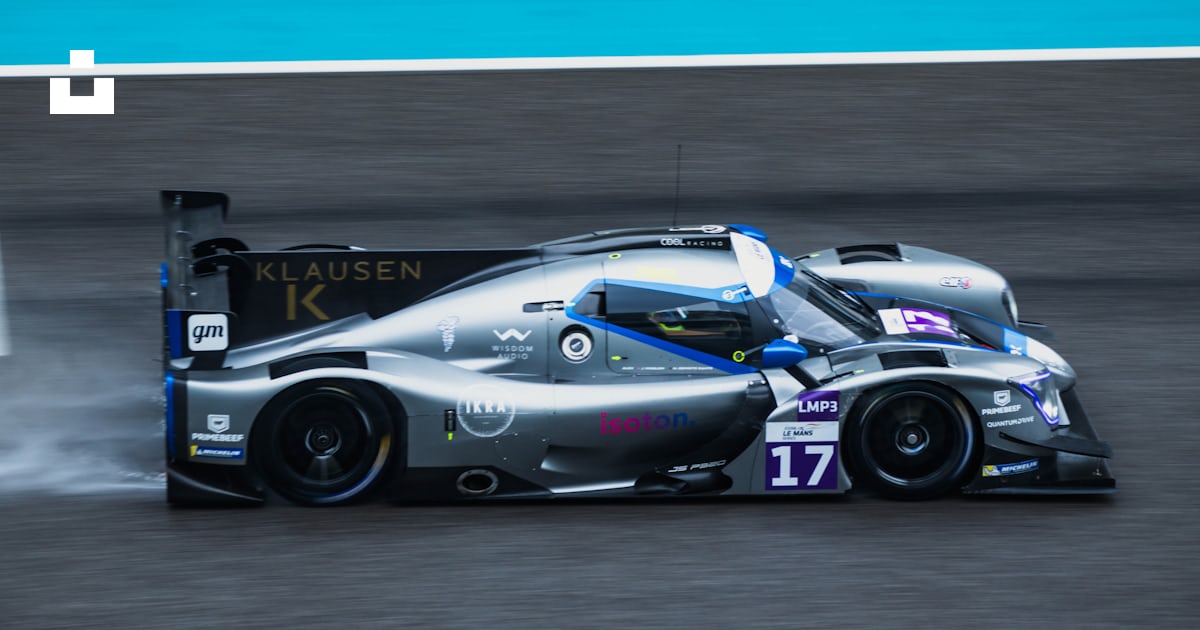 A silver race car driving down a race track photo – Free Car Image on ...