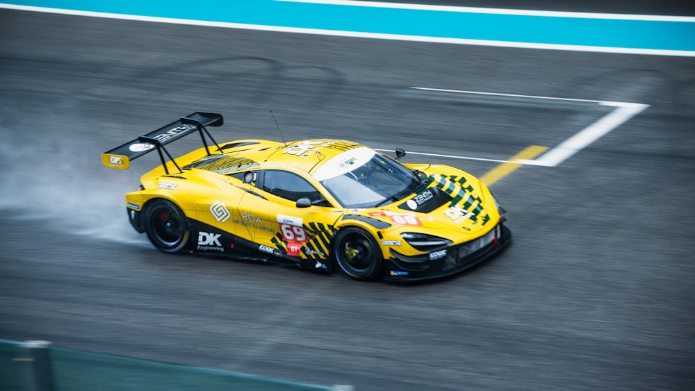 a yellow race car driving on a race track