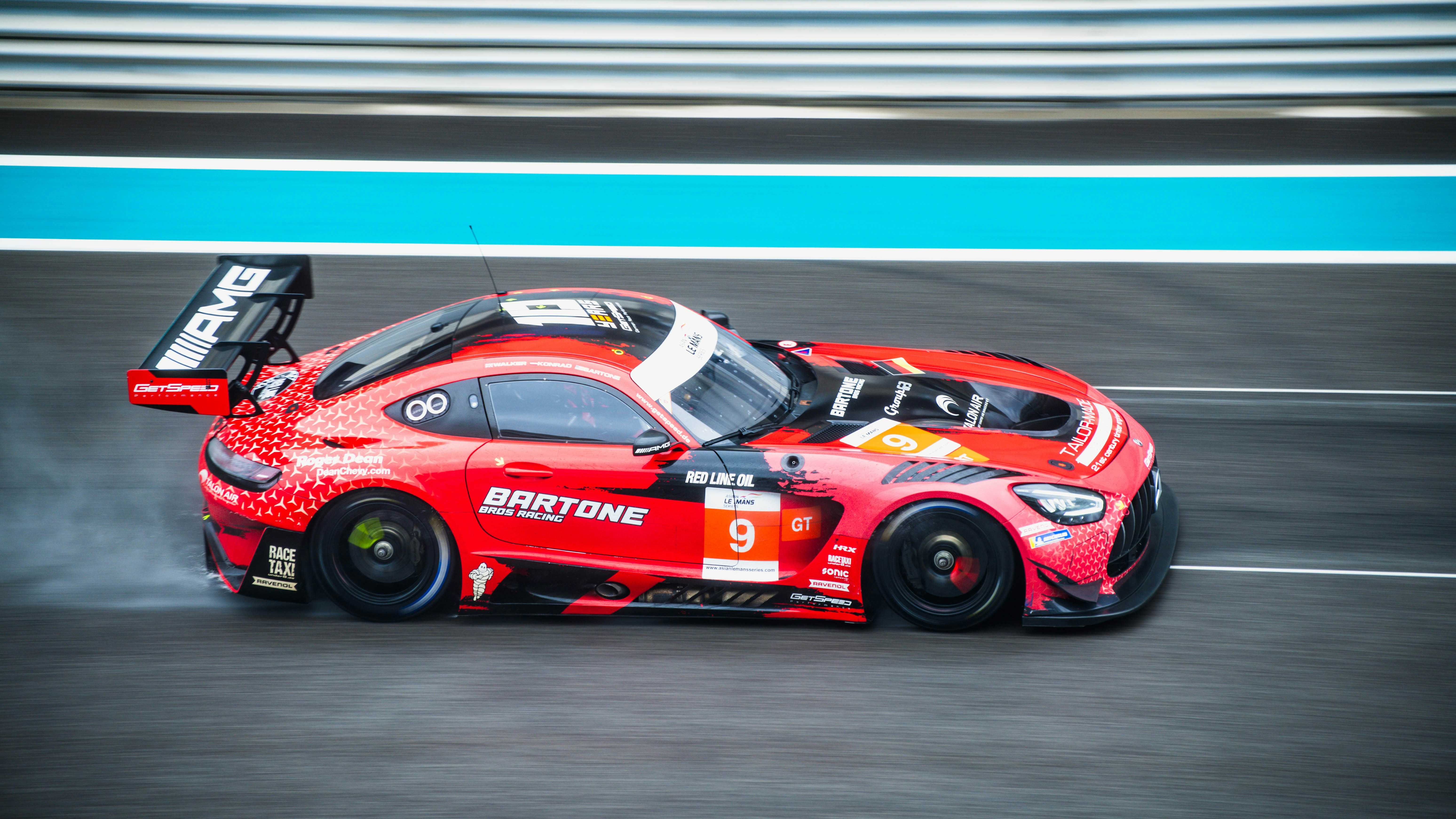 a red race car driving down a race track