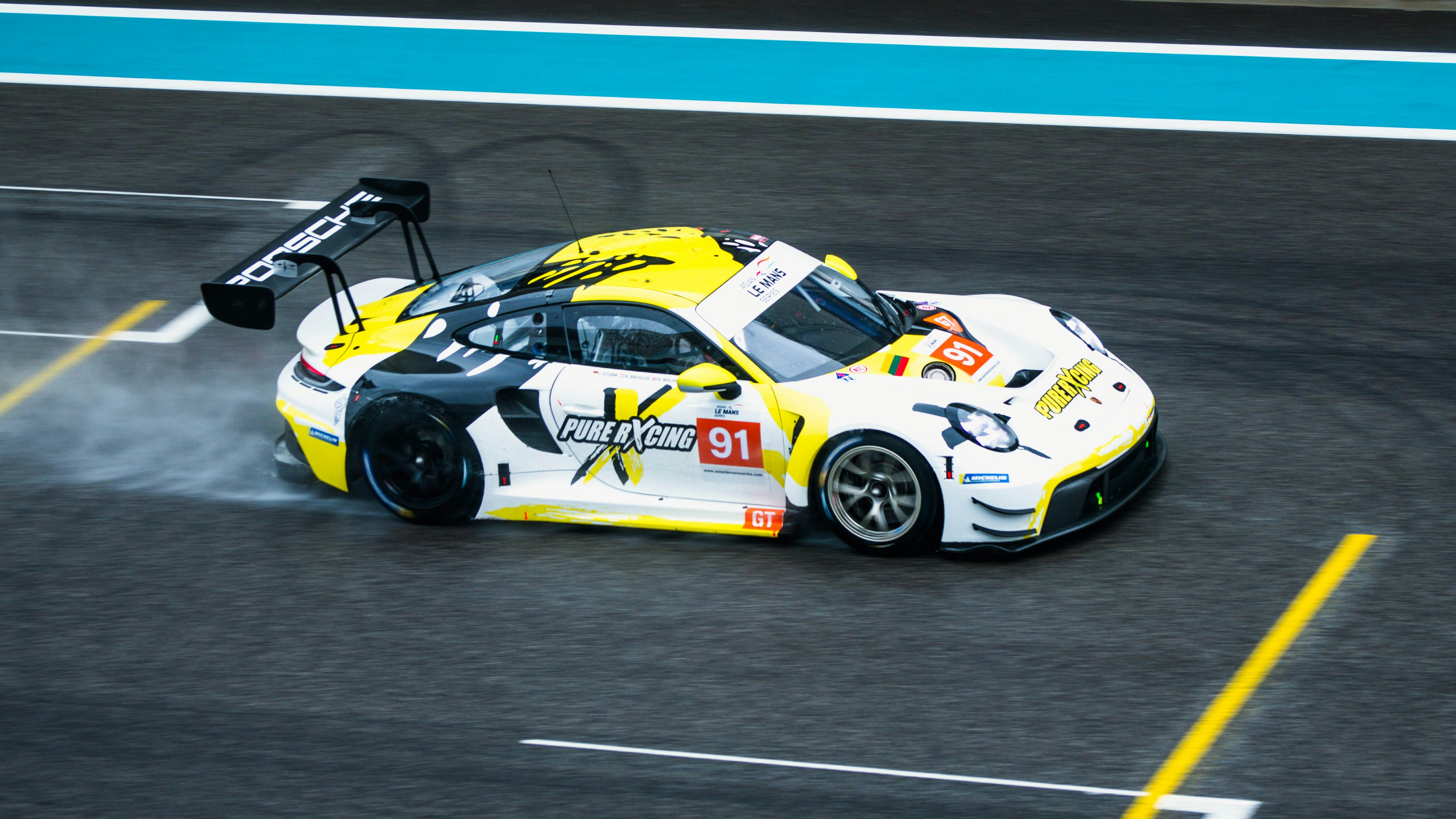 a yellow and white car driving on a race track