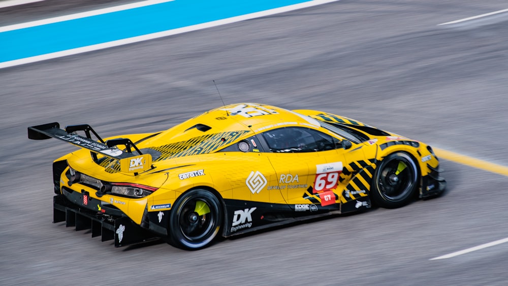 a yellow race car driving down a race track