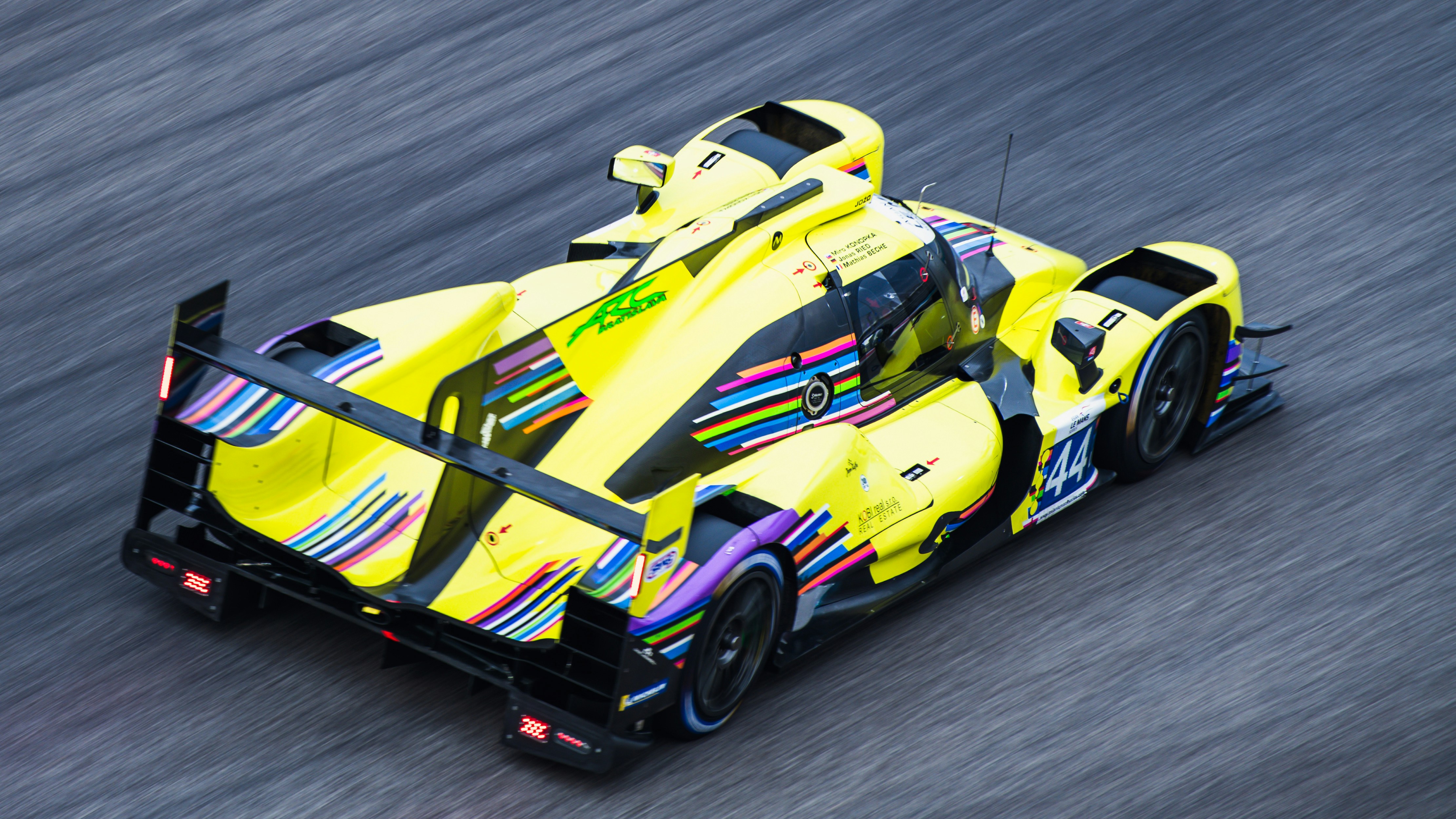 a yellow race car driving down a race track