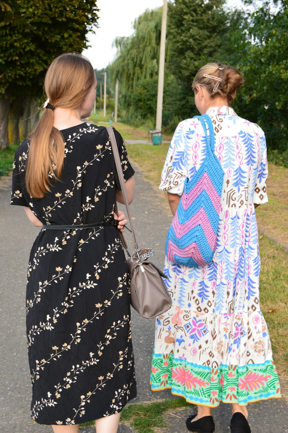 two women walking down a road with a handbag