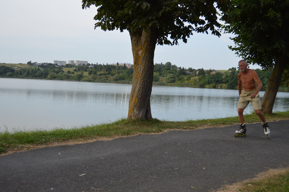 a man riding a skateboard down a road next to a lake