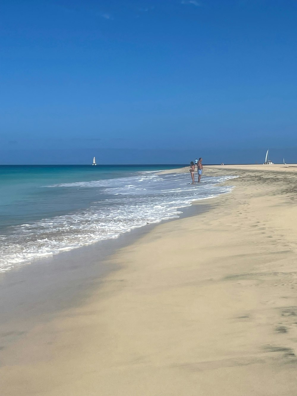 a couple of people walking along a beach next to the ocean