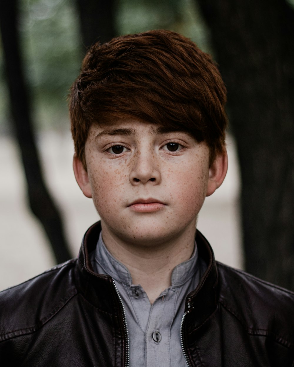 a young boy in a leather jacket looking at the camera