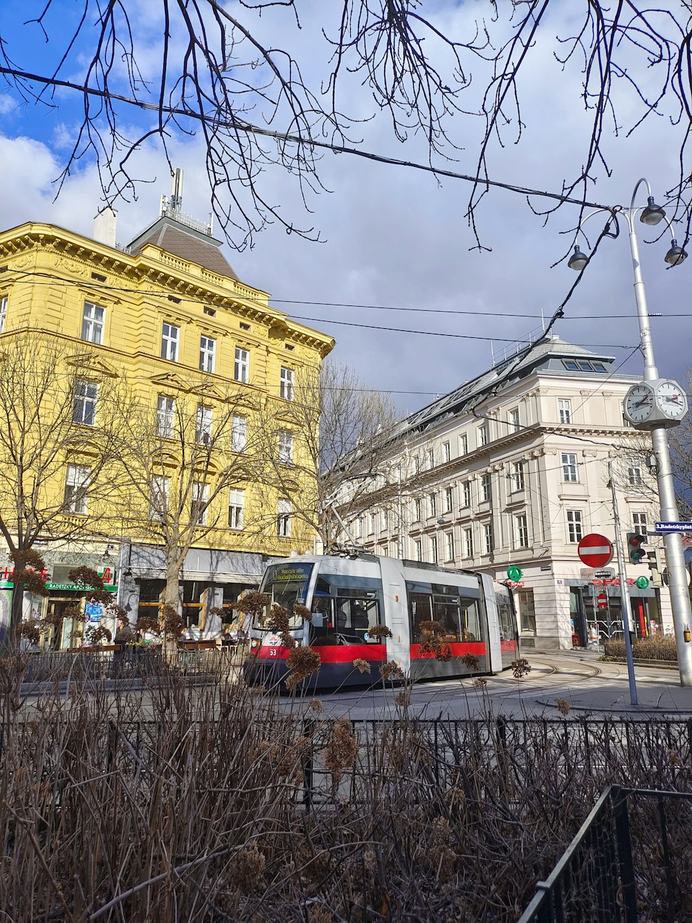 a red and white bus driving down a street next to tall buildings