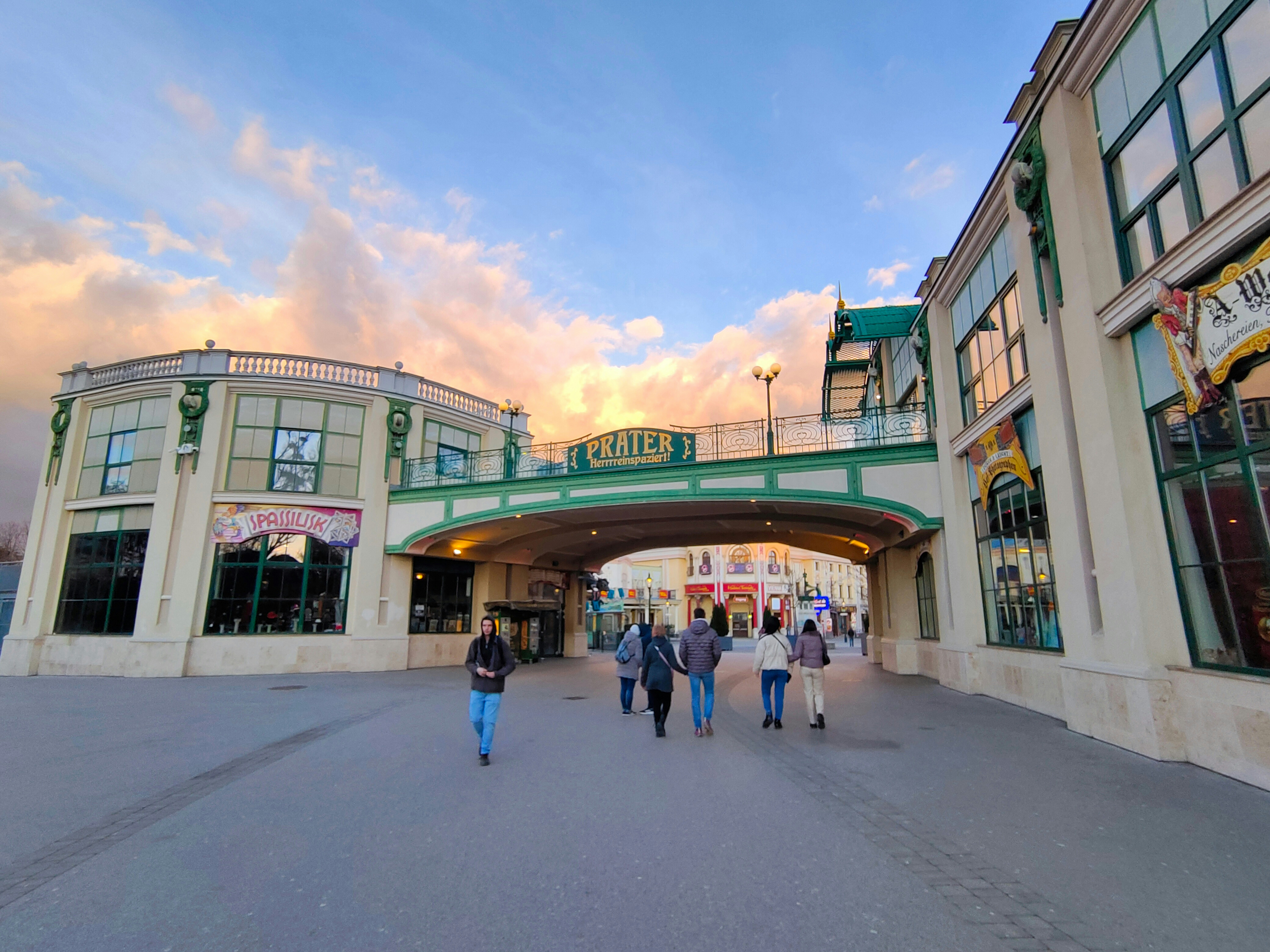 a group of people walking down a street under a bridge, 