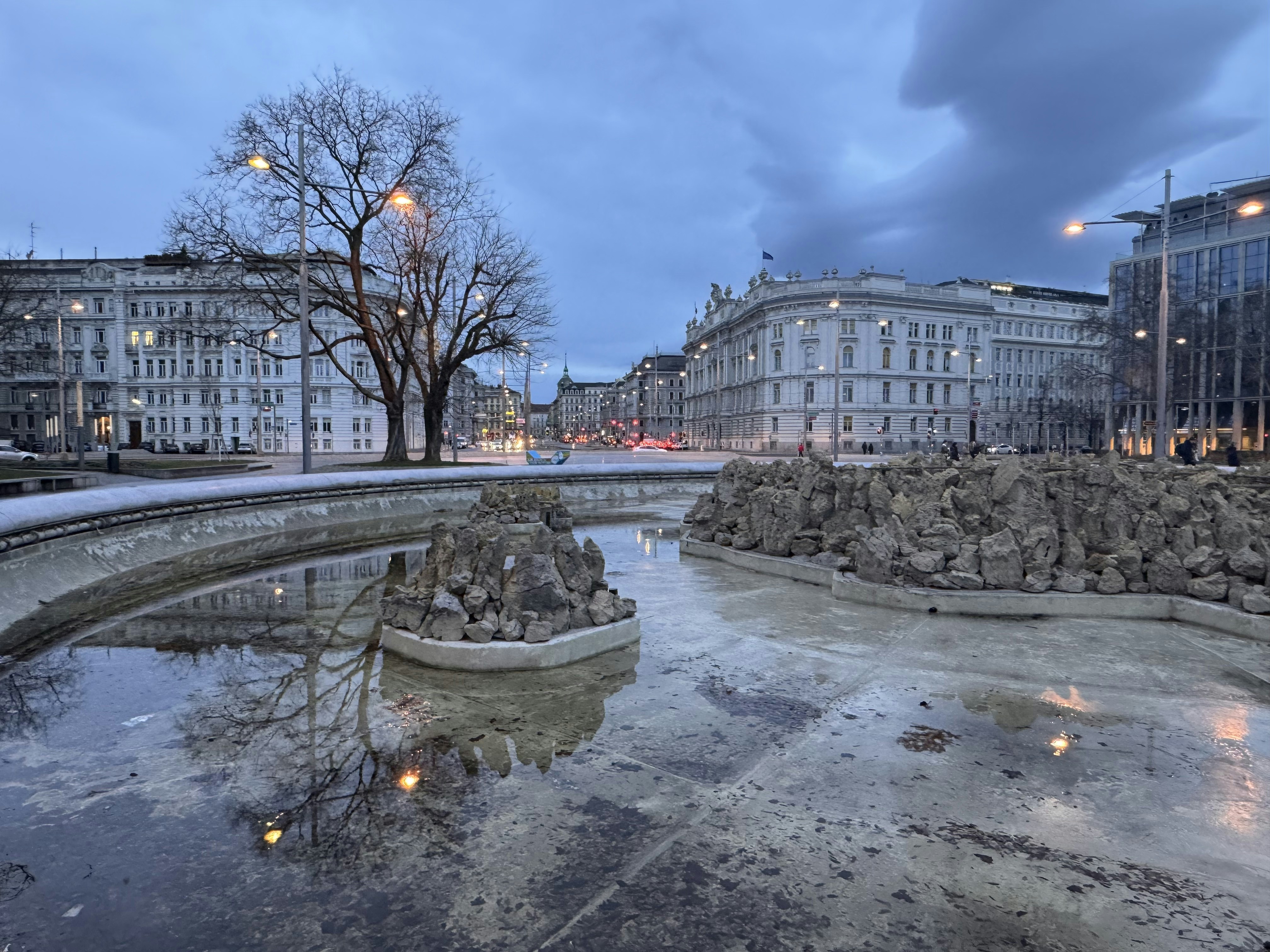 a fountain in the middle of a city at night, 