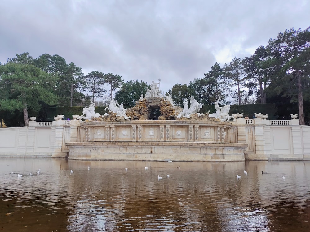 a pond with a fountain surrounded by white statues