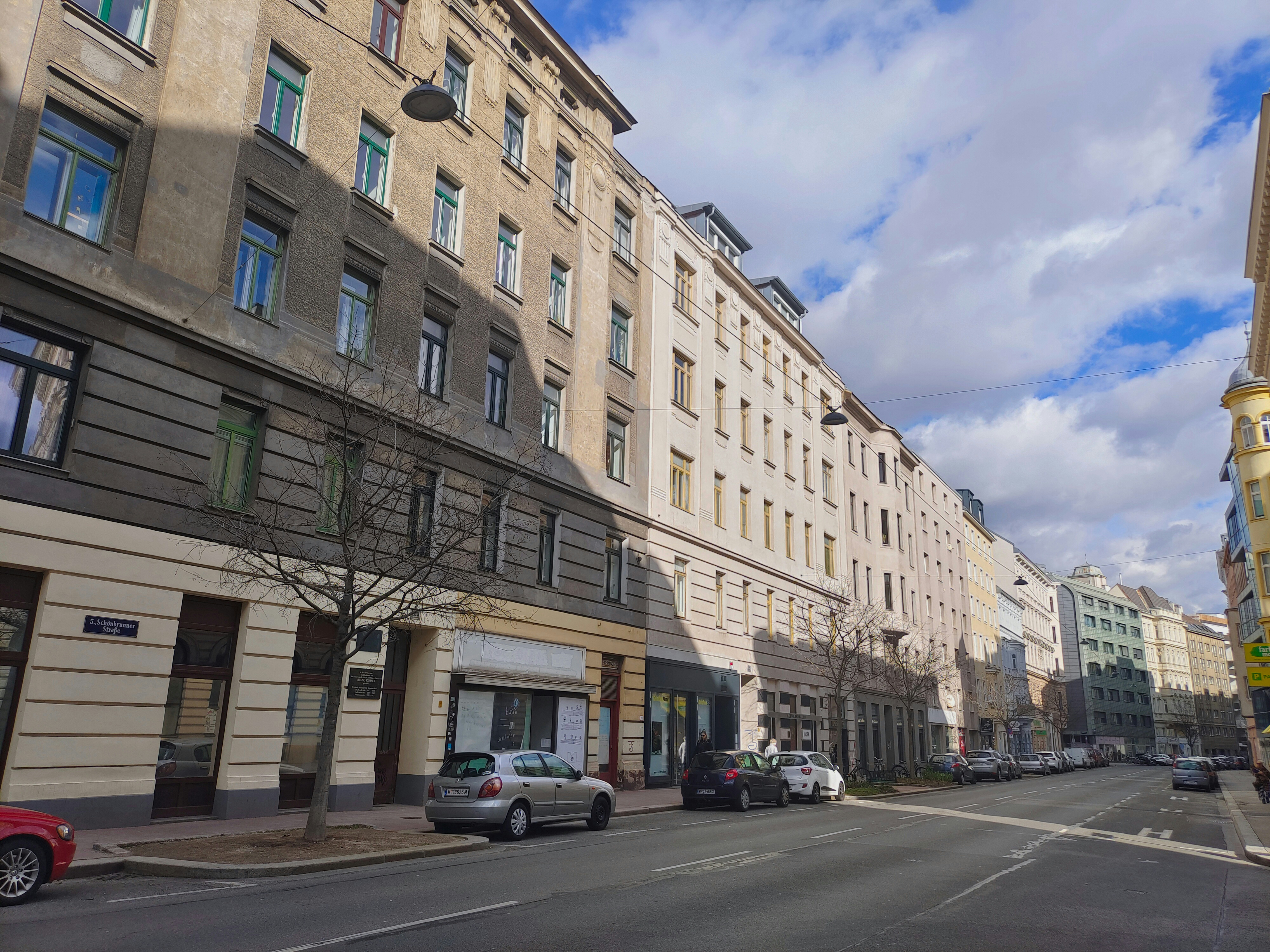 a city street lined with tall buildings and parked cars, 