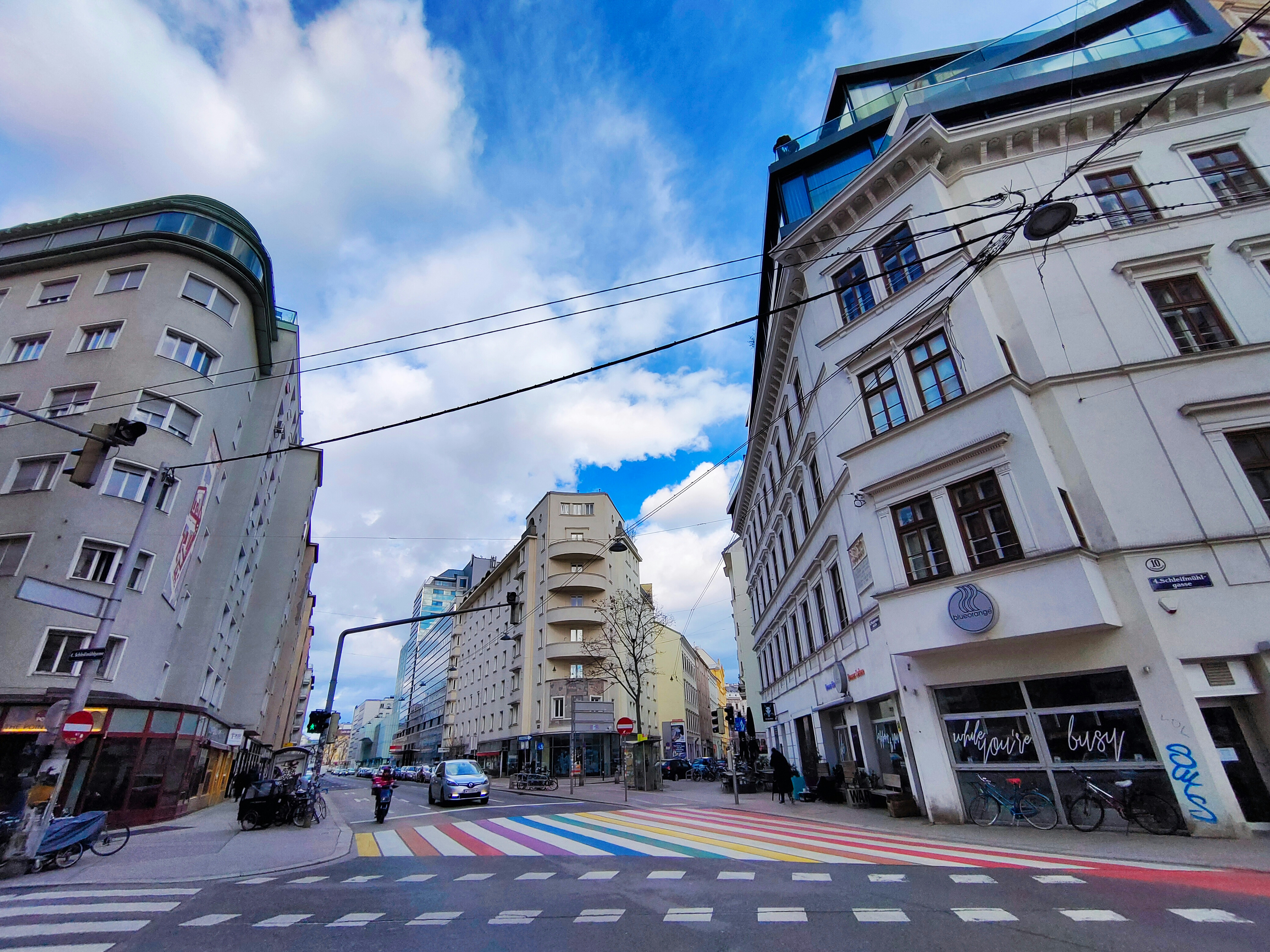 a city street with buildings and a rainbow painted crosswalk