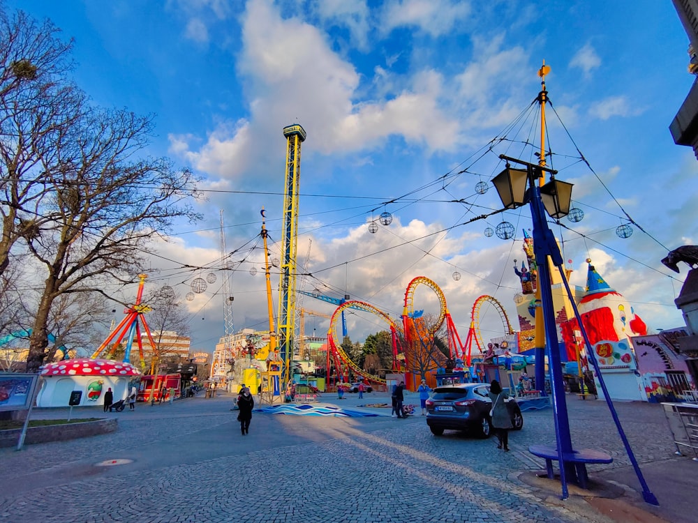 a man walking down a street next to carnival rides