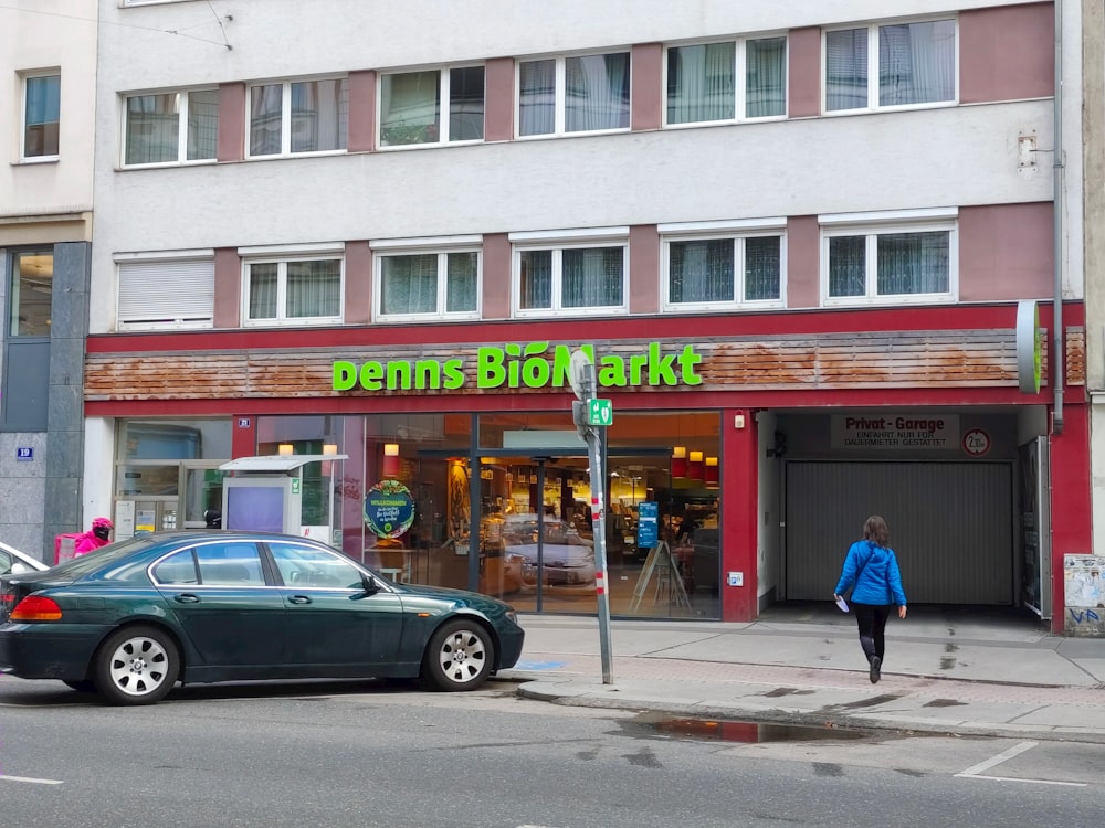 a woman walking down a street in front of a store