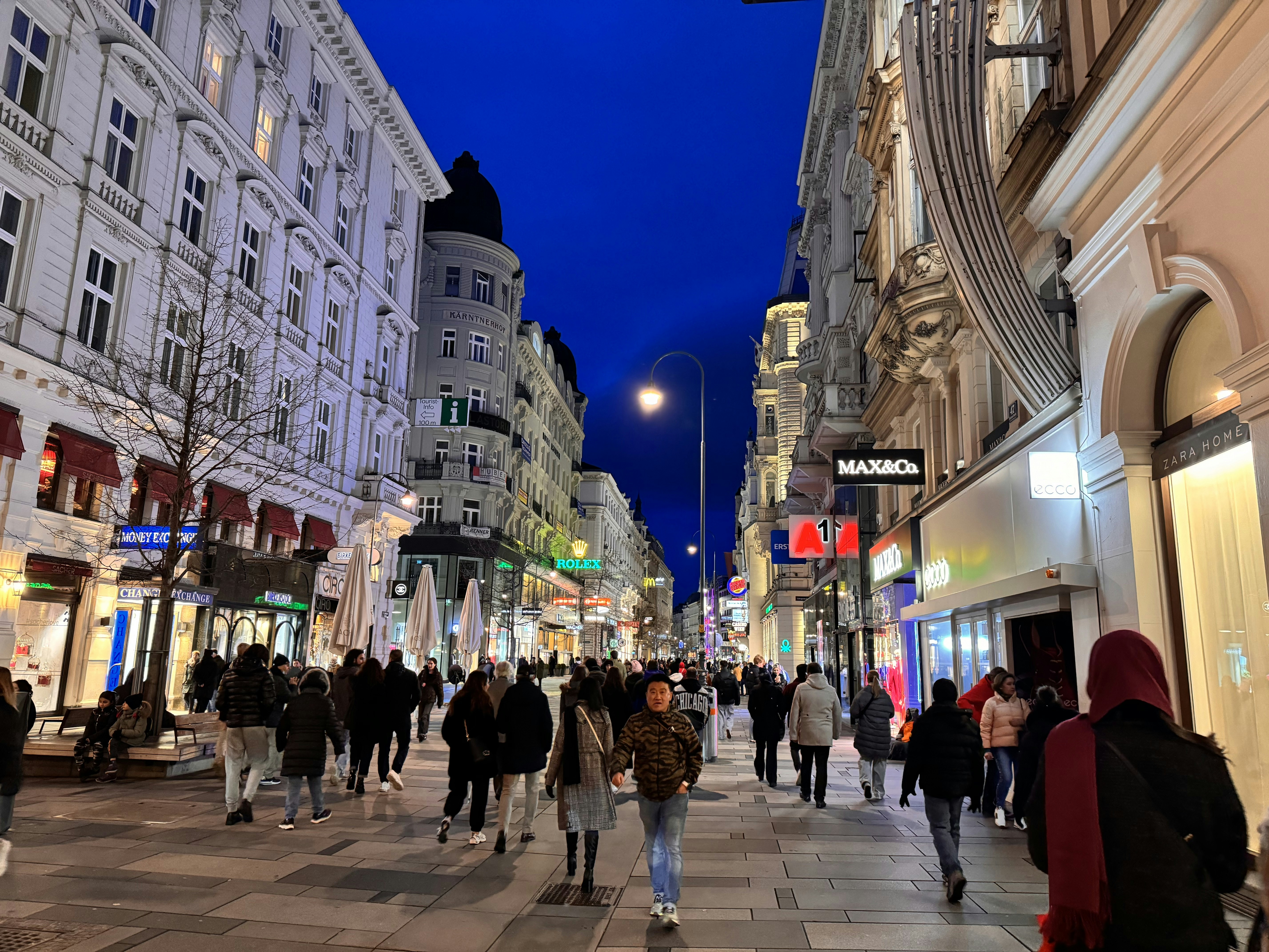 a group of people walking down a street next to tall buildings