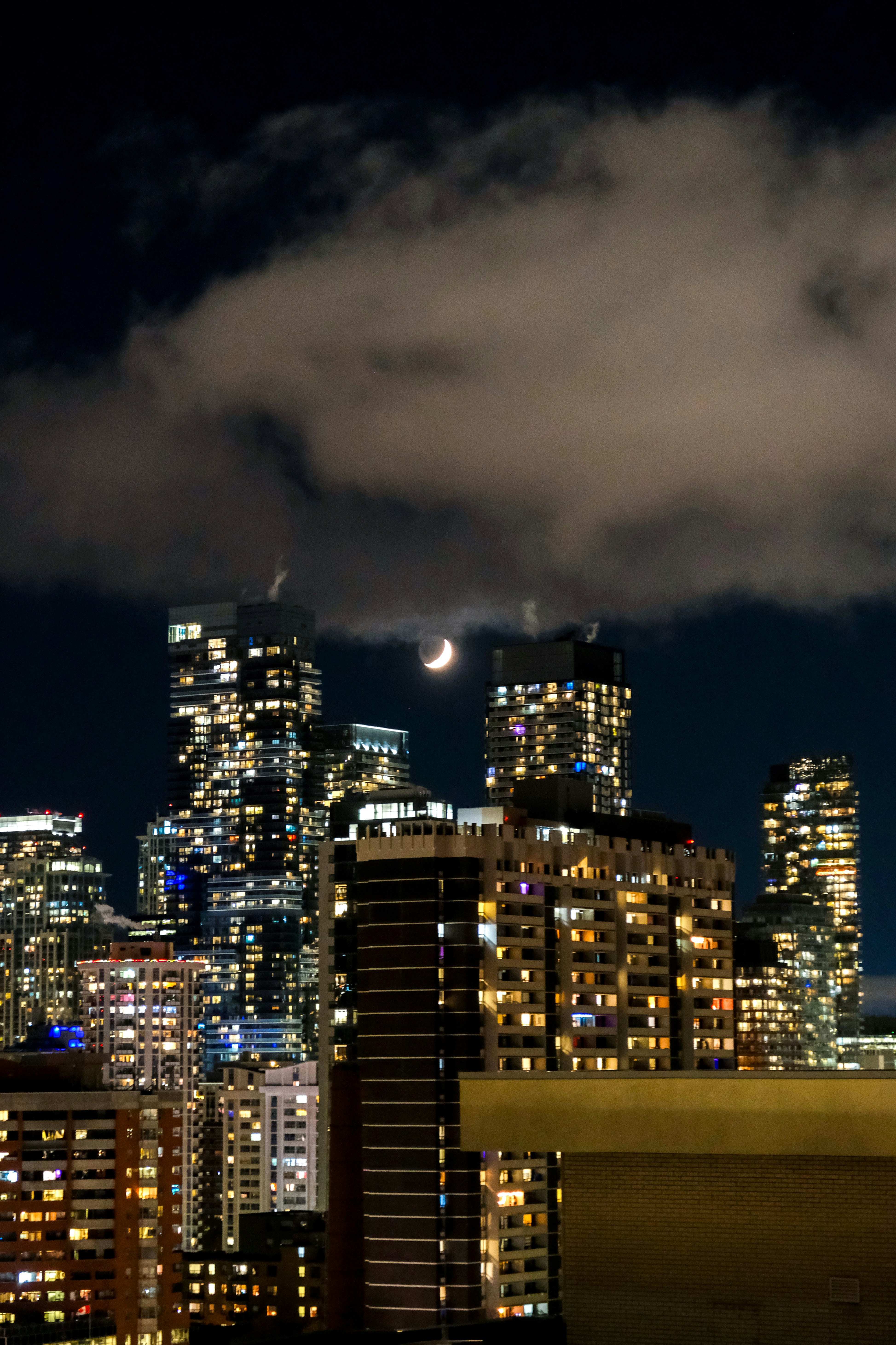 A view of a city at night with the moon in the sky photo – Free Toronto ...