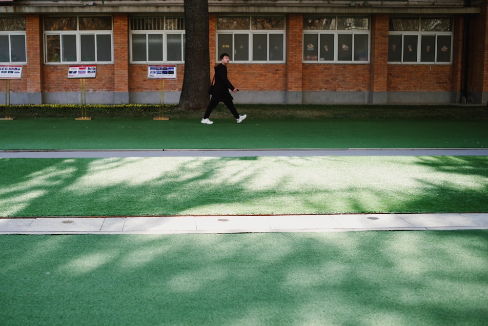 a man walking down a sidewalk next to a tree