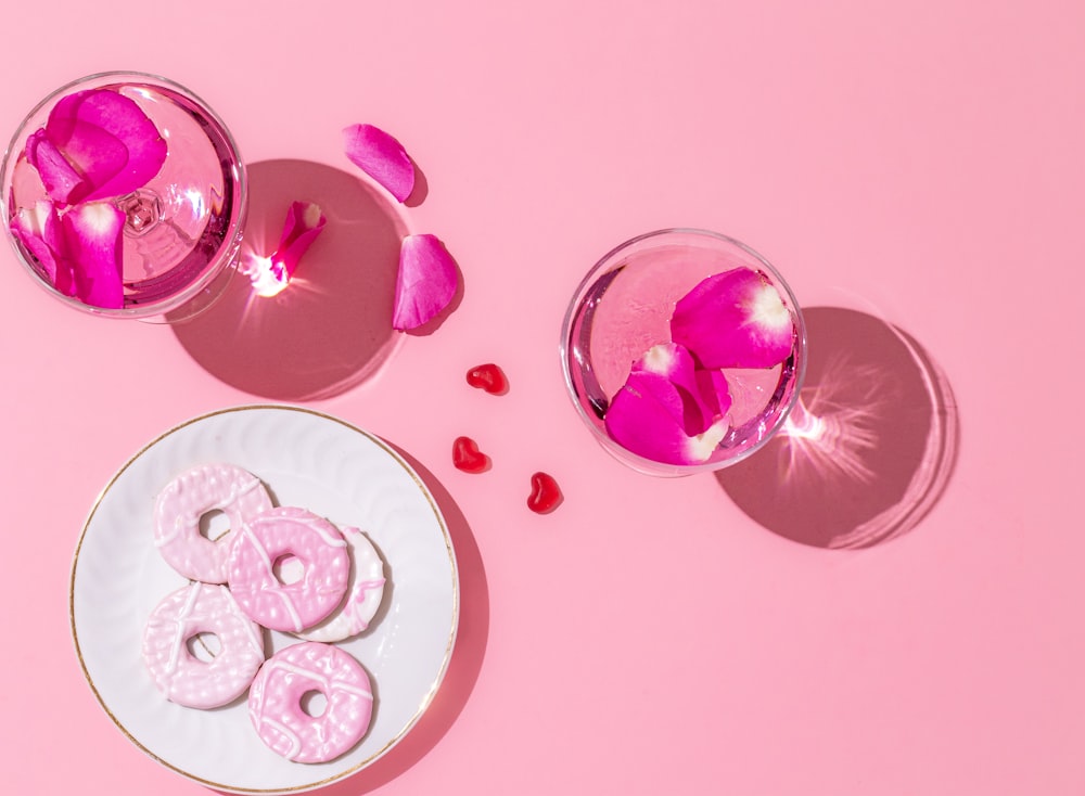 a plate of cookies and a glass of water on a pink background
