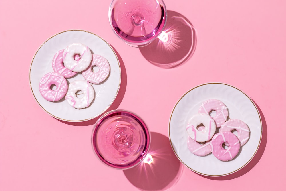 a pink table with three plates of doughnuts