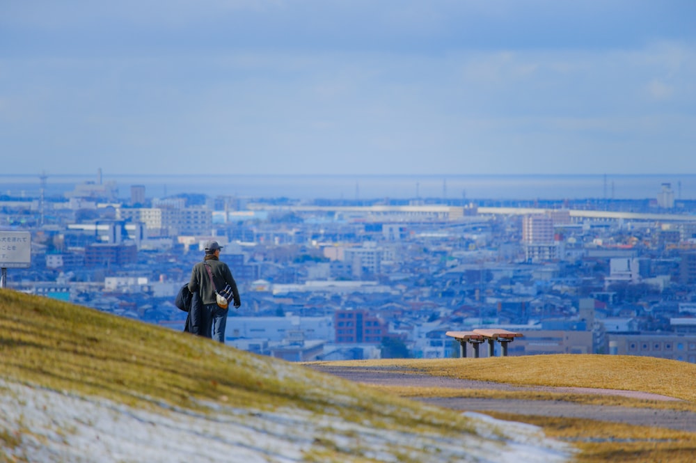 a man standing on top of a hill overlooking a city