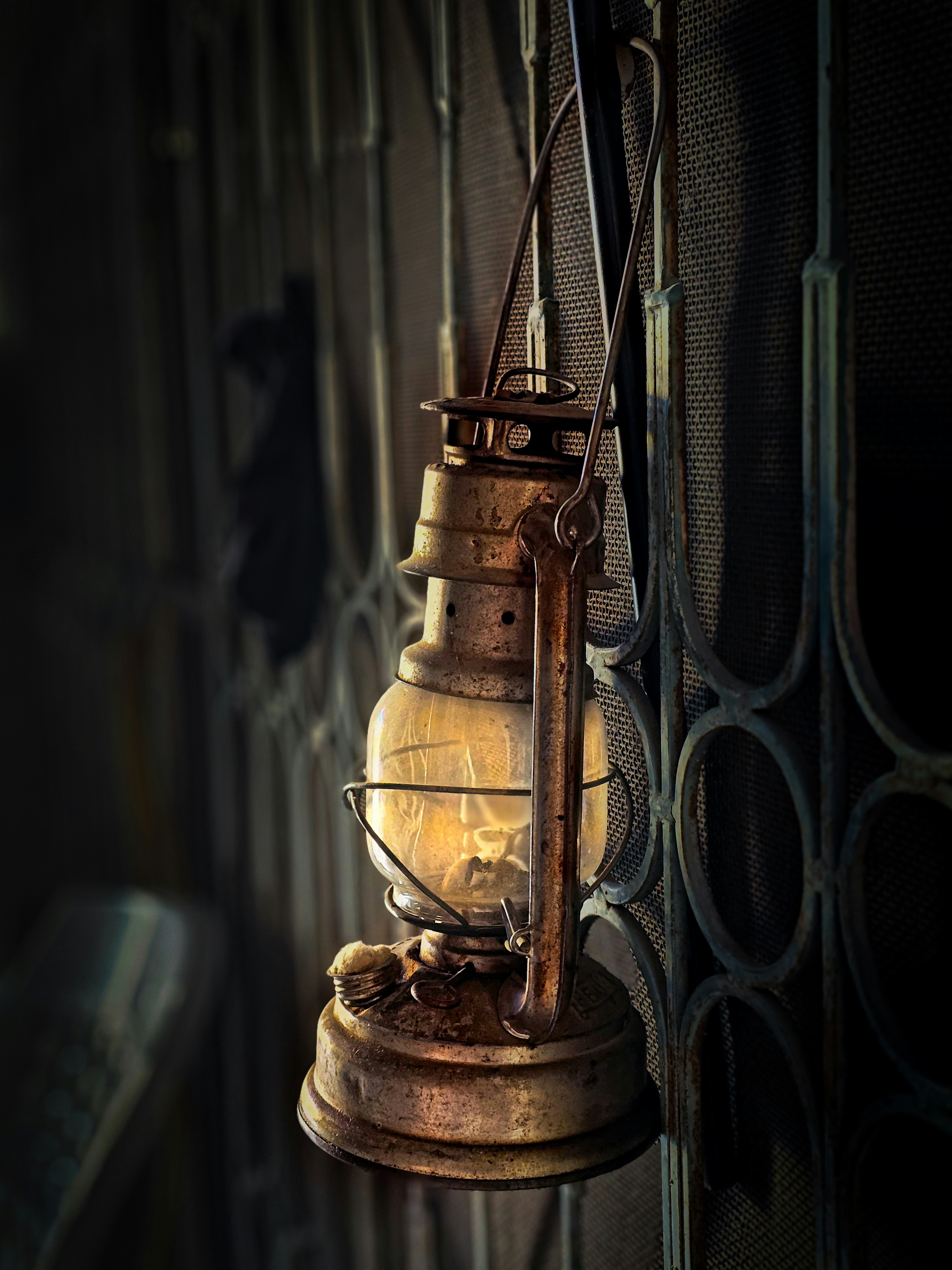an old light hanging from a metal fence