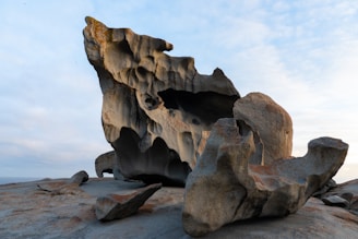 a rock formation on a beach with a sky background
