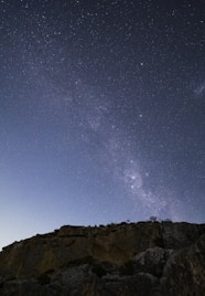 a person standing on top of a mountain under a night sky