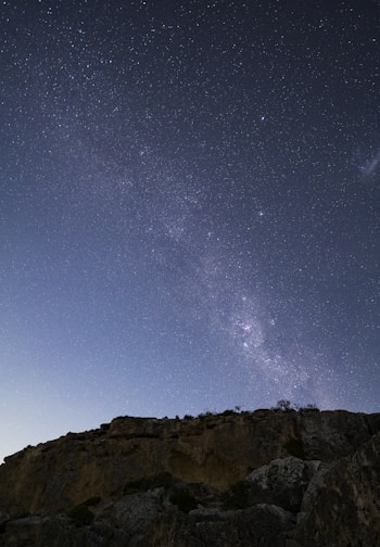 a person standing on top of a mountain under a night sky