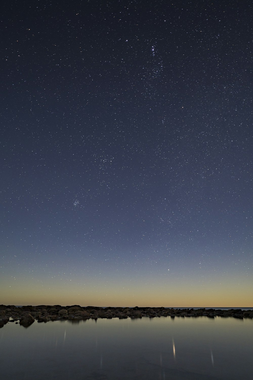 a body of water under a night sky filled with stars