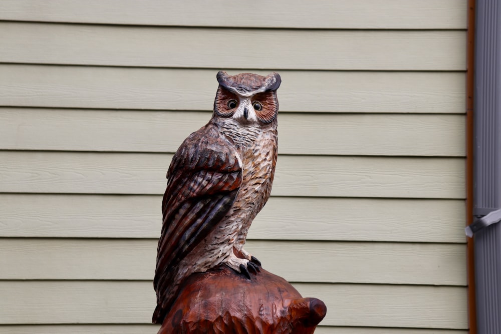 a statue of an owl sitting on top of a wooden stump