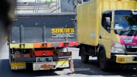 a yellow truck driving down a street next to a yellow truck