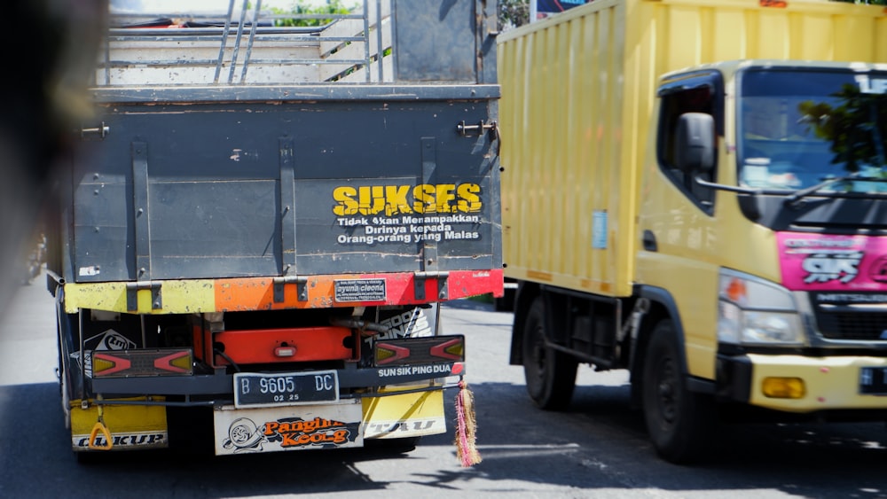 a yellow truck driving down a street next to a yellow truck