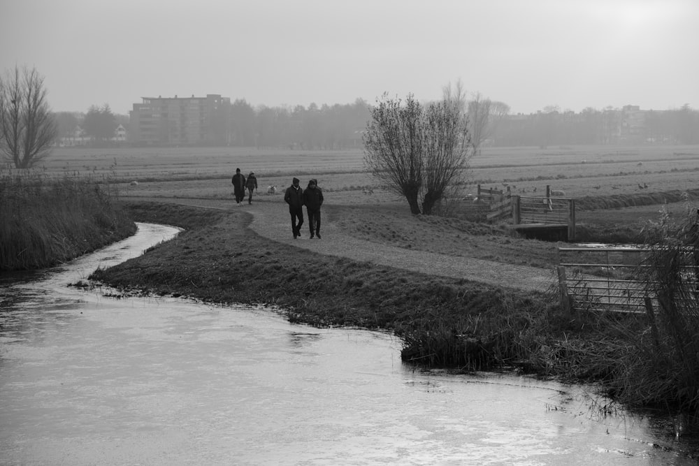 a group of people walking down a path next to a river