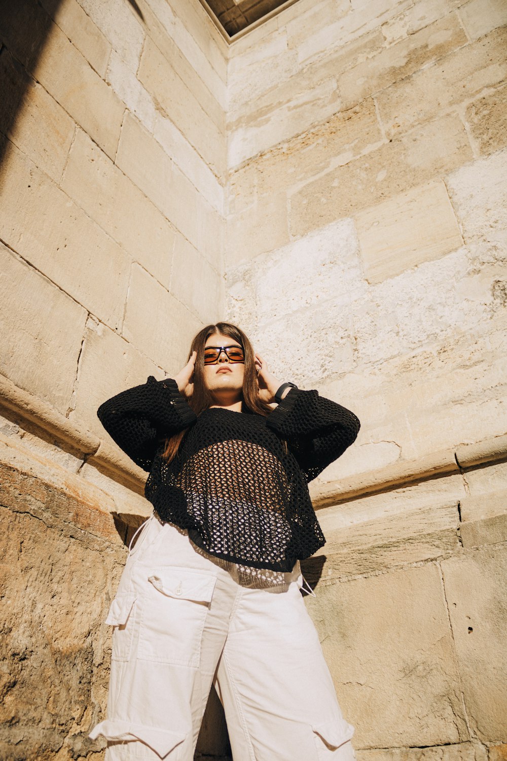 a woman standing in front of a stone wall talking on a cell phone