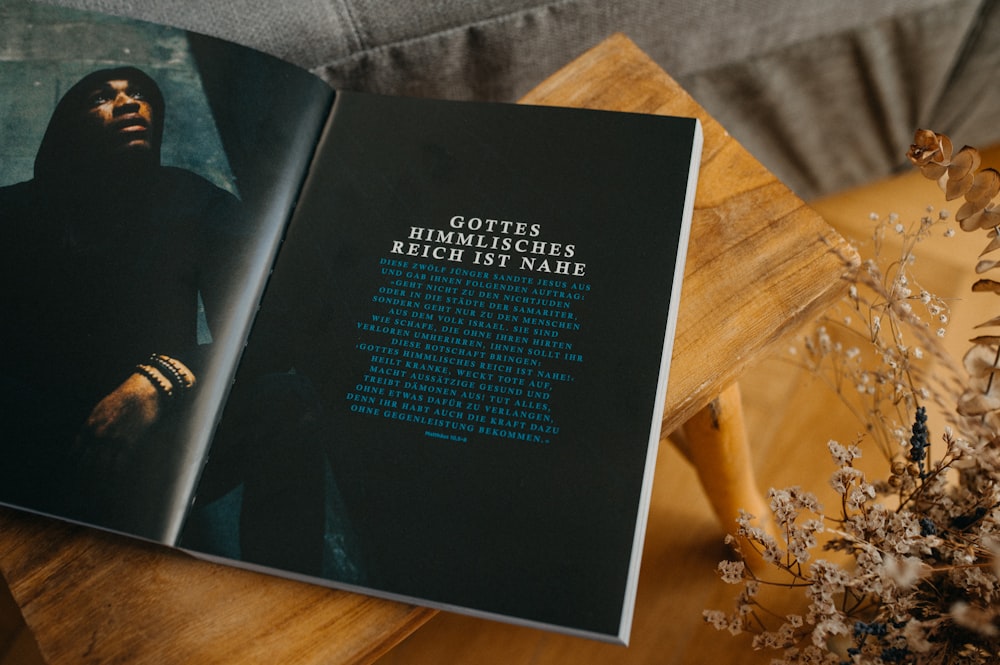 a book opened on a table with a vase of flowers