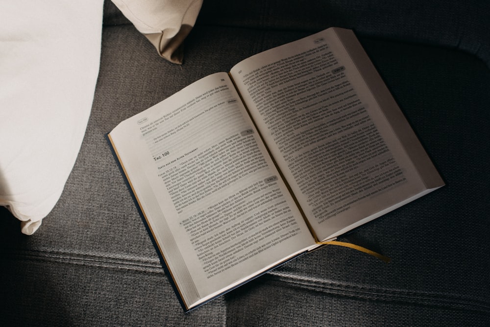 an open book sitting on a couch next to a pillow