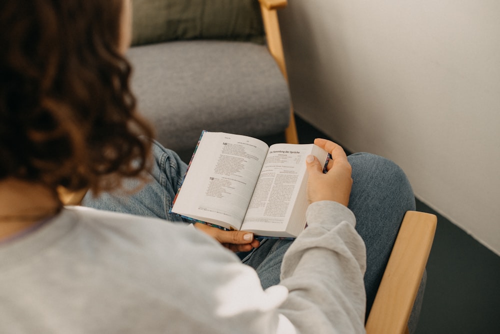 a woman sitting in a chair reading a book