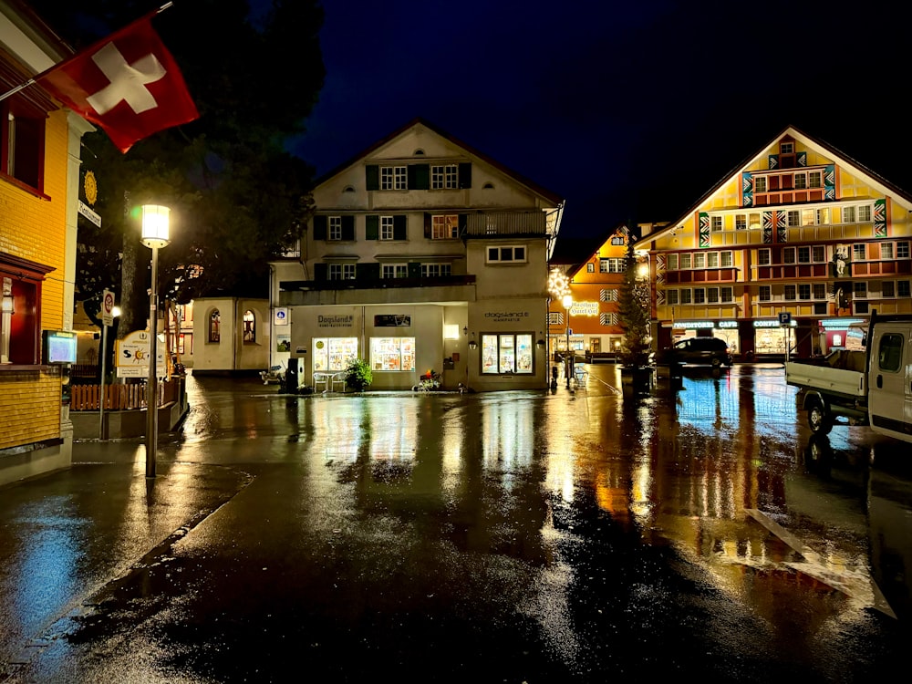 a city street at night with buildings and a swiss flag